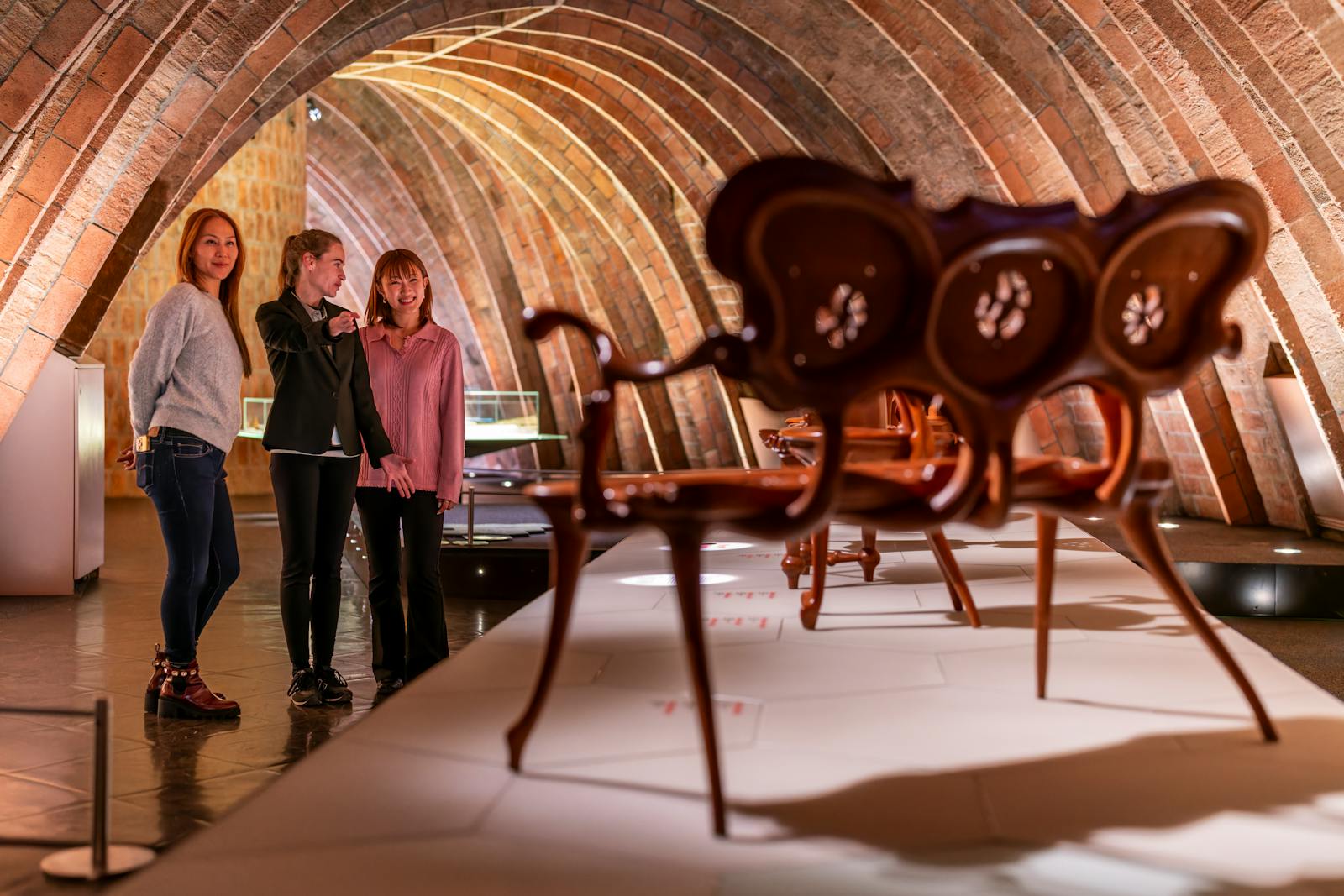 Bezoekers bewonderen meubels onder de gewelven van Casa Milà - La Pedrera